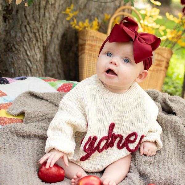 Baby wearing a cream personalized name knit sweater