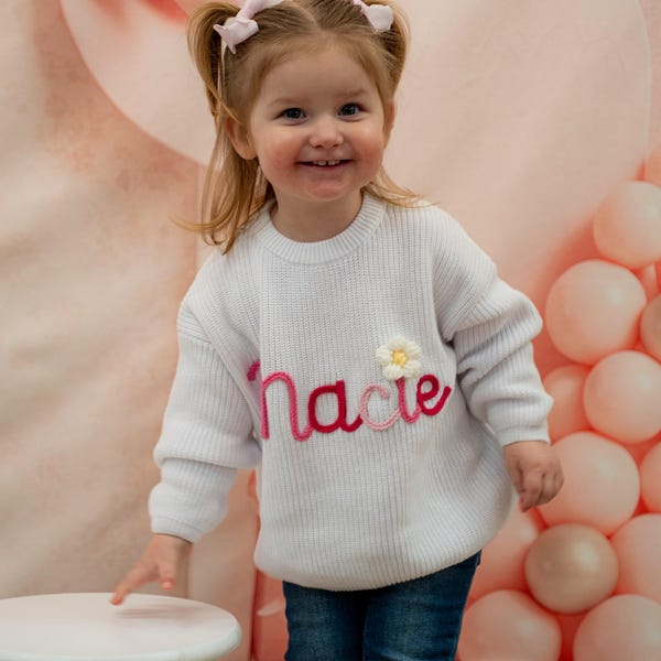 Toddler wearing a white personalized name knit sweater