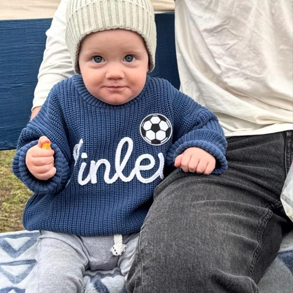 Baby wearing a navy personalized name knit sweater