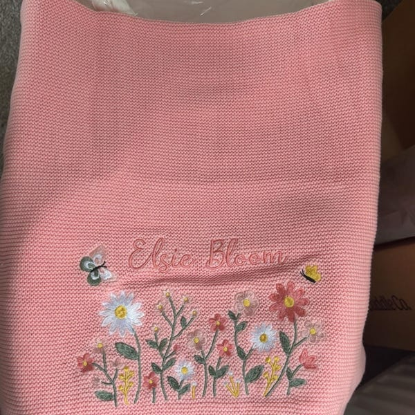 Blush knit baby blanket embroidered with a name and wildflowers