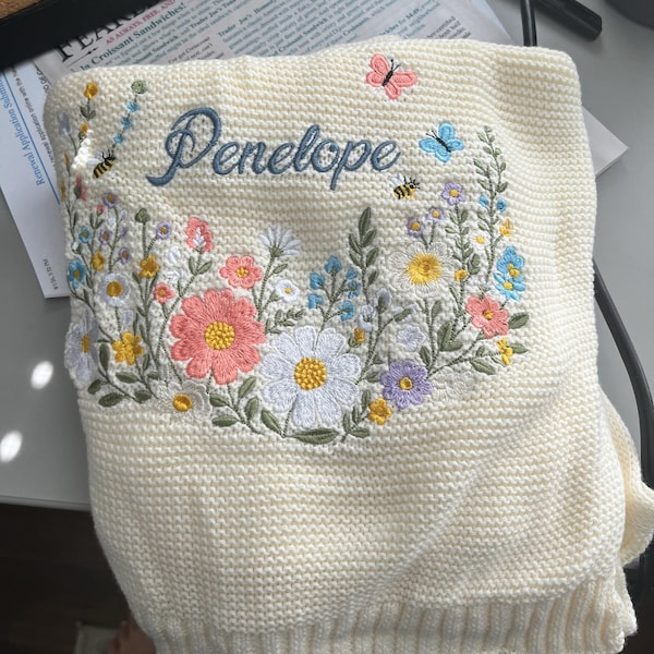 Close-up of the embroidered name and floral detail on a knit blanket