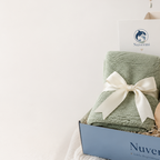 Sage green personalized knit baby blanket folded with a cream ribbon in a Nuvermi gift box